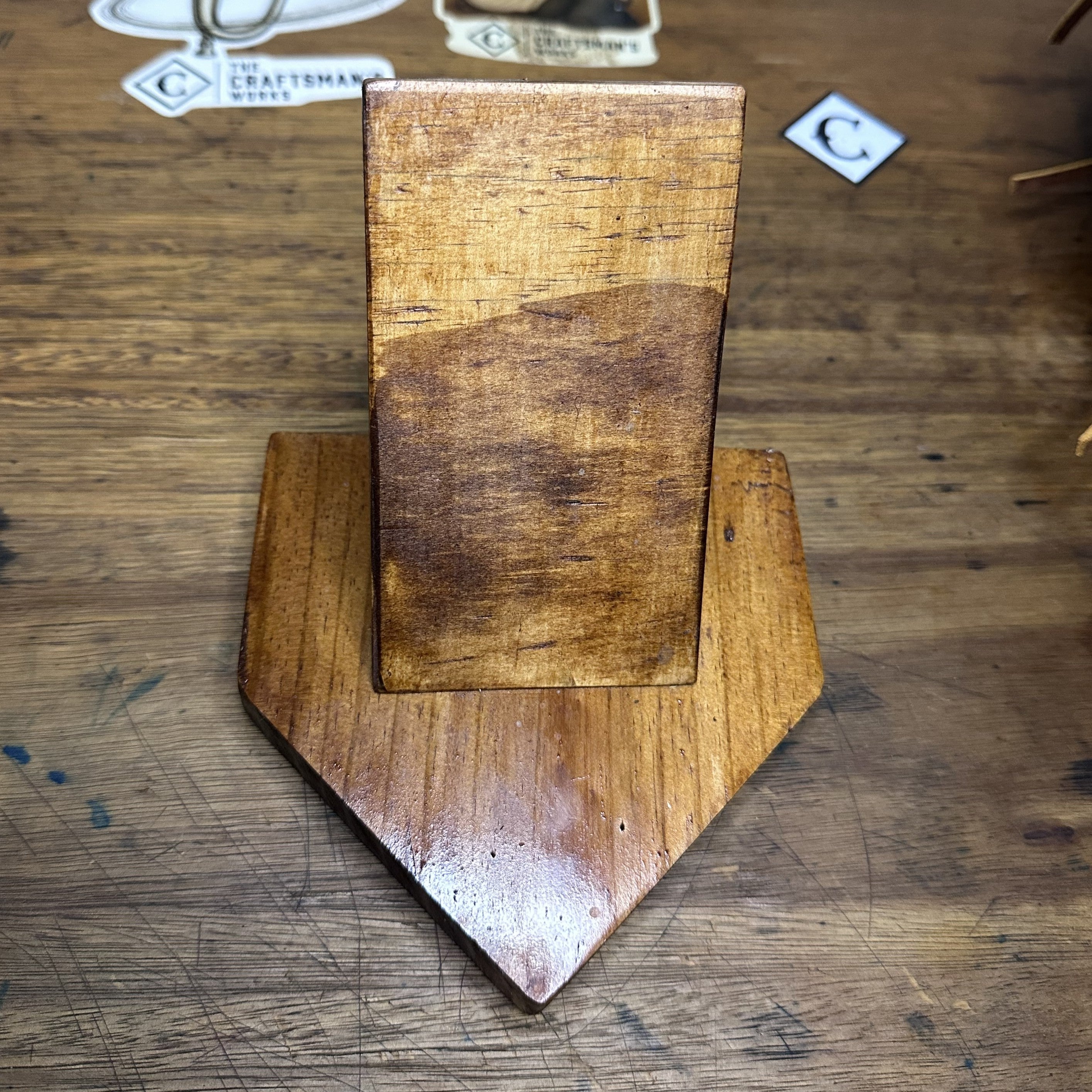 Wooden baseball glove display stand with a stained home-plate-shaped base holding a leather baseball glove