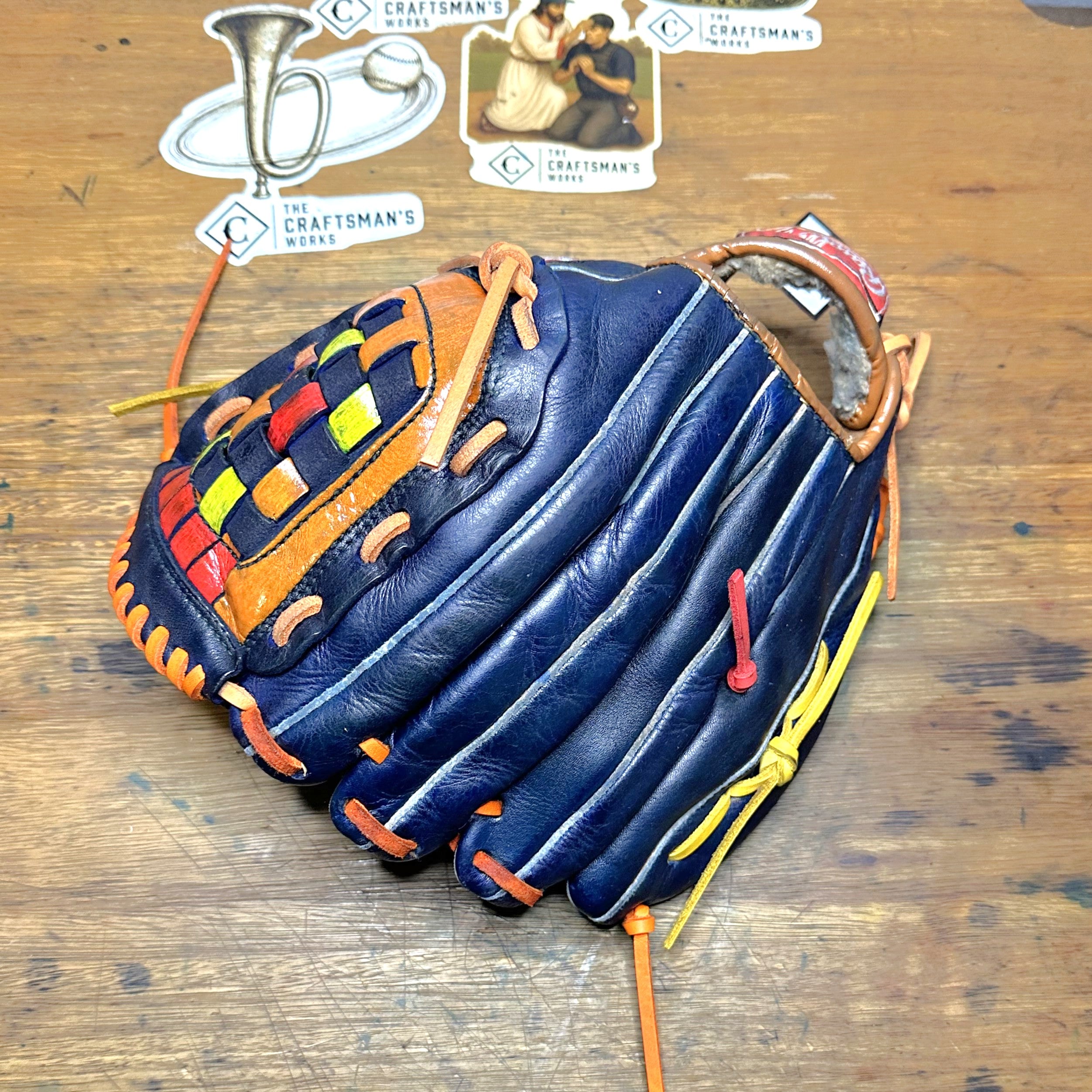 The Tequila Sunrise Nolan Ryan RBG60 glove laying on a desk with the back and finger side facing up.