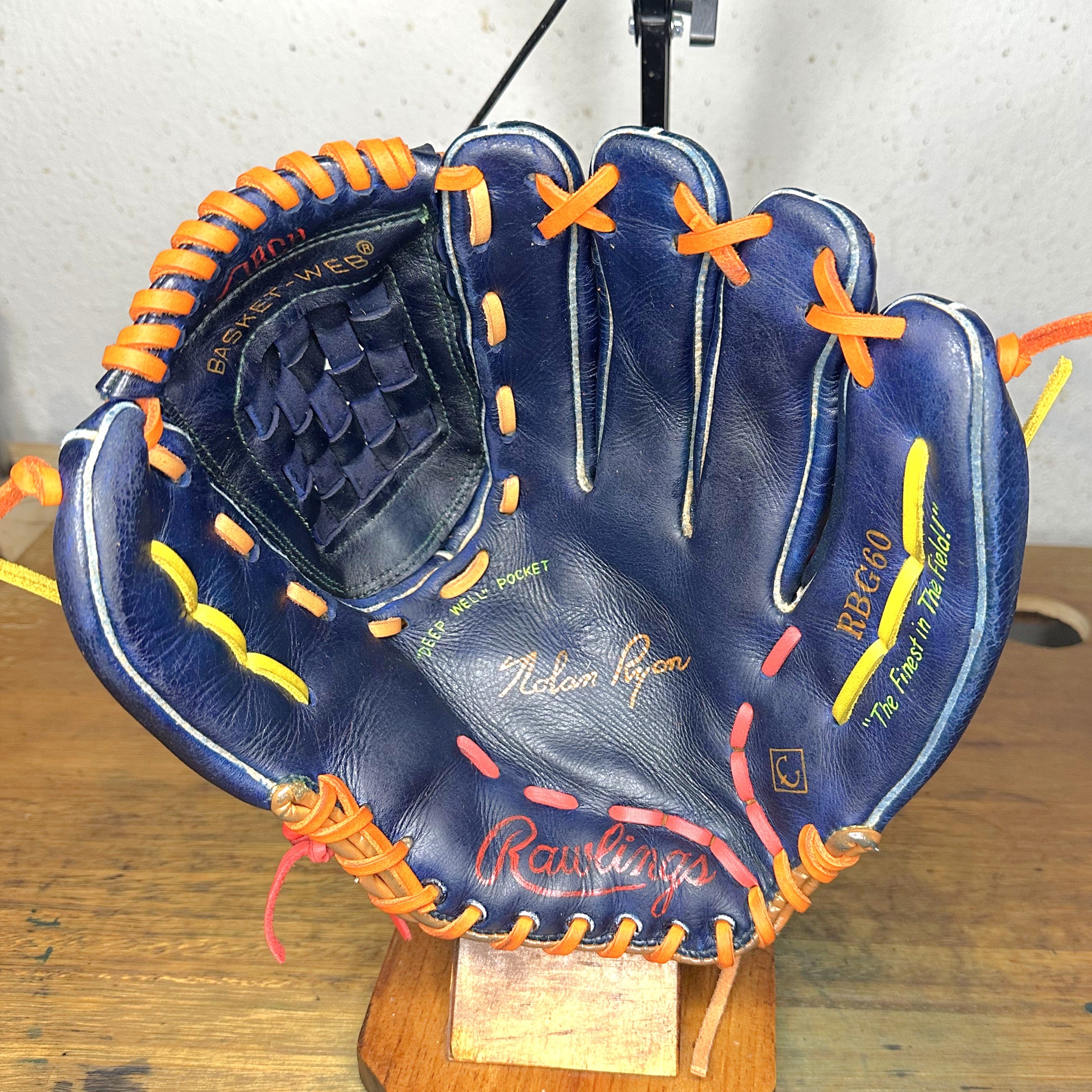 The Tequila Sunrise Nolan Ryan RBG60 glove sitting on a stand with the palm side facing up.